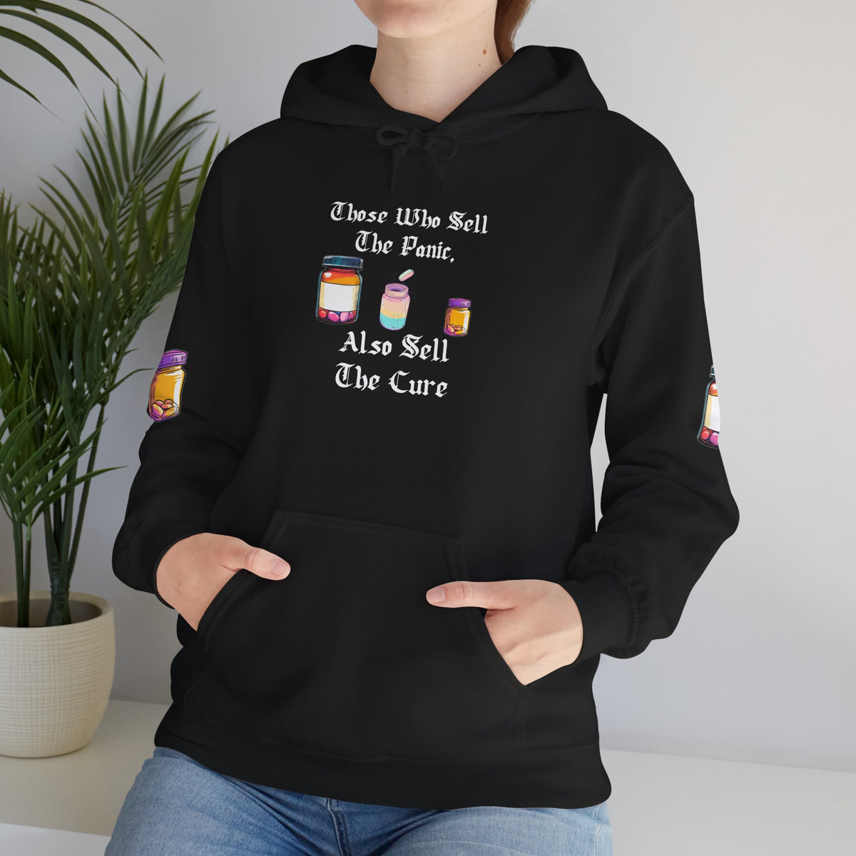 Black hoodie with gothic blackletter text “Those Who Sell the Panic, Also Sell the Cure” and three colorful pill bottles